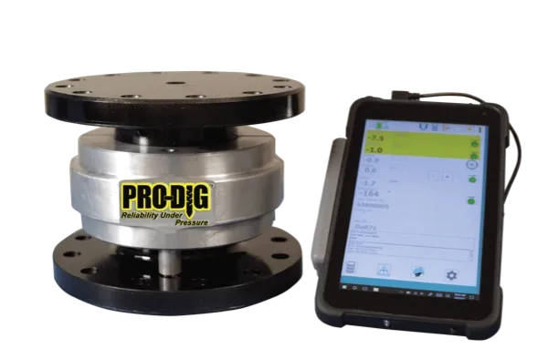 A round metallic load cell with a "PRO-DIG" logo is connected to a digital display device showing measurements. The device is black with a touchscreen interface, displaying numeric data and a green highlighted section.